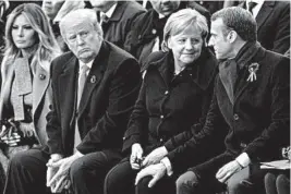  ?? FRANCOIS MORI/GETTY-AFP ?? French President Emmanuel Macron and German Chancellor Angela Merkel sit with President Donald Trump and first lady Melania Trump on Sunday at the Arc de Triomphe in Paris.