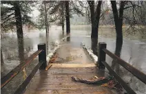  ?? Michael Macor / The Chronicle ?? Yosemite’s Swinging Bridge led to a trail covered with water from the Merced River.