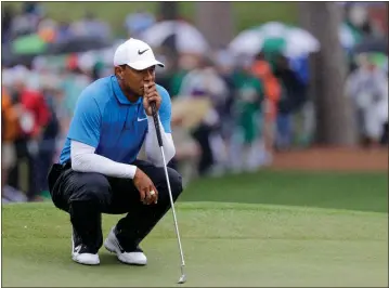  ?? David J. Phillip / AP ?? Tiger Woods lines up his putt in the rain on the seventh hole during the third round at the Masters in Augusta.