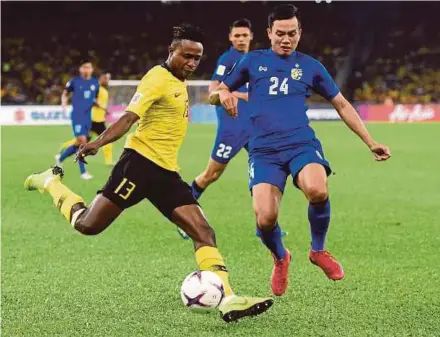  ??  ?? Malaysia’s Mohamadou Sumareh (left) takes a shot as Thailand’s Korrakot Wiriyaudom­siri goes for the block during their AFF Cup semi-final match at the National Stadium in Bukit Jalil on Saturday.