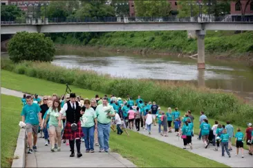  ??  ?? ABOVE: Cast Off Against Cancer participan­ts make their way to the pedestrian bridge to drop daisies into the Oostanaula in honor or in memory of someone with cancer.