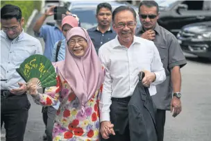  ?? AFP ?? Politician Anwar Ibrahim and his wife Wan Azizah, a former Malaysian deputy prime minister, leave their home in Kuala Lumpur yesterday.