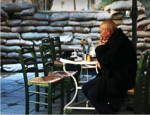  ?? Foto: Reuters/Yiannis Kourtoglou ?? Leben an Nikosias Grüner Linie, die von den Vereinten Nationen bewacht wird: Kaffeehaus­atmosphäre im Schatten einer Wand aus Sandsäcken