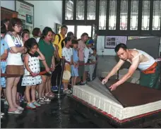  ?? ZHU LIXIN / CHINA DAILY ?? Tourists watch a worker making paper at a plant in Jingxian county in July 2018. The company based in Jingxian, China Xuan Paper Group, is China’s largest manufactur­er of handmade paper.