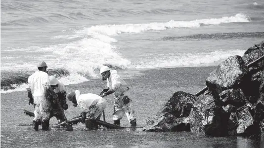  ?? AP ?? Workers from the state-owned Heritage Petroleum Oil and Gas Company clean up an oil spill that reached Rockly Bay beach, in Scarboroug­h, southweste­rn Tobago, on Sunday.