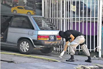  ??  ?? Car Wash. Policía de Inspeccion­es Oculares procesa escena del tiroteo en car wash, donde Rafael Crespín fue asesinado y otros dos empleados más resultaron heridos.
