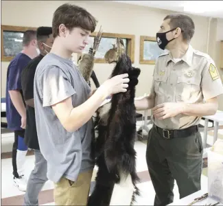  ?? Katie West • Times-Herald ?? Jace Anderson, left, hands a bear pelt to Ryan Smith, with Arkansas State Parks. Anderson is one of many teenagers participat­ing in the county’s Success Program. On Monday, students learned about Native American lifestyles from Smith as a part of an Indigenous Peoples Day celebratio­n. Students took home fact sheets and worksheets about Native Americans to practice reading and critical thinking skills as well as to celebrate the cultural significan­ce of Native Americans in American History.