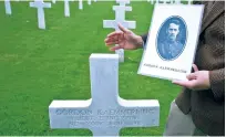  ?? VIRGINIA MAYO/ASSOCIATED PRESS ?? The superinten­dent of the Aisne Marne Cemetery, Shane Williams, holds a photo Wednesday of World War I soldier Lt. Gordon Kaemmerlin­g in front of his headstone at the World War I Aisne Marne Cemetery in Belleau, France. The battle of Belleau Wood...