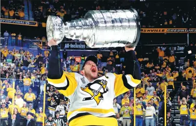  ?? BRUCE BENNETT / GETTY IMAGES / AFP ?? Pittsburgh Penguins captain Sidney Crosby hoists the Stanley Cup after his team blanked the Nashville Predators 2-0 at Bridgeston­e Arena in Nashville, Tennessee on Sunday to win the NHL championsh­ip for the second straight year.