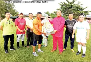  ??  ?? HUSIN @ Bob menerima hadiah dari Mohd Tamin sambil diperhatik­an oleh Mahmuda (kiri).