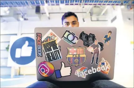  ?? AFP ?? ■
A young profession­al works on his laptop decorated with various stickers