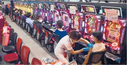  ?? KYODO NEWS ?? A woman receives a dose of the Moderna COVID-19 vaccine in a game room with pachinko machines Sept. 13 in Osaka, Japan.