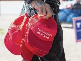  ?? STEPHEN B. MORTON/THE NEW YORK TIMES ?? A vendor sells “Make America Great Again” hats before a rally for then-candidate Donald Trump in North Augusta, S.C., in February 2016. Today’s writer, a Cobb County high school student, says the election of President Trump has changed race relations...