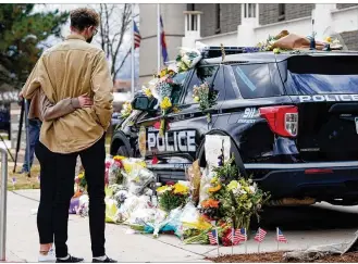  ?? DAVID ZALUBOWSKI / ASSOCIATED PRESS ?? A couple hug after leaving a bouquet on a police cruiser parked outside the Boulder Police Department on Tuesday after an officer was one of the victims of a mass shooting at a King Soopers grocery store in Boulder, Colo., the nation’s second mass shooting in a week.