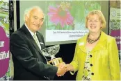  ??  ?? Pictured is Jane Hollingwor­th, Quorn in Bloom co-ordinator, receiving the Best Park trophy from Doug Stacey, president of the East Midlands in Bloom.
