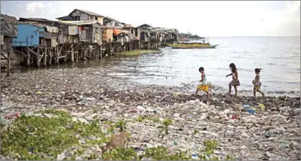  ?? NOEL CELIS/AFP ?? Children walk along a garbage-filled bay in Manila. About eight million tonnes of plastic waste are dumped into the world’s oceans every year – the equivalent of one garbage truck of plastic being tipped into the sea every minute of every day.