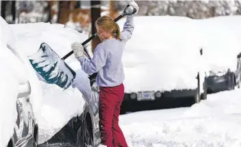  ?? DAVID ZALUBOWSKI AP ?? Nine Lillehei clears snow off her vehicle Monday after a powerful late winter storm dumped more than 2 feet of snow in Denver. The storm shut down major roadways, canceled school and closed the state Legislatur­e.