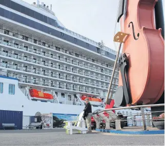  ?? GREG MCNEIL • CAPE BRETON POST ?? People pose under the big fiddle in front of the Joan Harriss Cruise Pavilion in Sydney in front of the Riveria of Oceania during the 2019 cruise ship season. The 2020 cruise ship season at the Port of Sydney was cancelled.