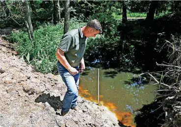 ?? [PHOTO BY MIKE SIMONS, TULSA WORLD] ?? Scott Engelbrech­t of J-M Farms on a dam that the company made on Tar Creek in Miami last week. A recent spill at the farms caused a fish kill in Tar Creek.