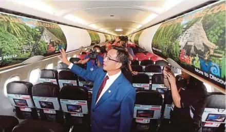  ?? PIC BY L. MANIMARAN ?? Sarawak Tourism, Arts, Culture, Youth and Sports Minister Datuk Abdul Karim Rahman Hamzah checking some of the visuals for the Visit Sarawak Campaign onboard an AirAsia aircraft at the Kuching Internatio­nal Airport yesterday.