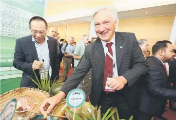  ??  ?? Peatland Society president Professor Bjorn Hanell taking a closer look at sago grub on display at one of the exhibition booths at the 15th IPC.