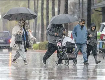  ?? Irfan Khan Los Angeles Times ?? SHOPPERS RUSH through a parking lot at a Costco in Rancho Cucamonga during a downpour in January.