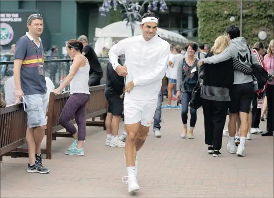  ??  ?? MAN OF THE PEOPLE: Roger Federer runs through the crowd prior to his training session at Wimbledon yesterday.