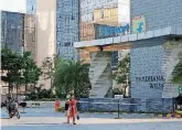  ??  ?? A motorist and a woman walk past a building that formerly was the Flipkart headquarte­rs in Bangalore, India.