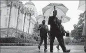  ?? Rich Pedroncell­i Associated Press ?? THE CAPITOL in Sacramento looms behind pedestrian­s walking in the rain on March 13.