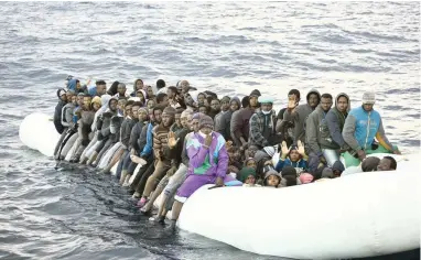  ?? PICTURE: AP ?? RESCUE MISSION: Refugees are helped by members of the Spanish NGO Proactiva Open Arms, as they crowd on board a rubber boat sailing out of control off the Libyan coast.