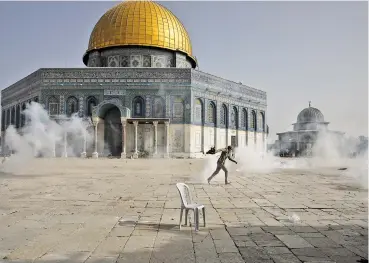  ?? MAHMOUD ILLEAN/ASSOCIATED PRESS ?? A Palestinia­n man runs away from tear gas Monday during clashes with Israeli security forces in front of the Dome of the Rock Mosque at the Al Aqsa Mosque compound in Jerusalem’s Old City. The confrontat­ions led Hamas in the Gaza Strip to fire rockets toward Jerusalem.