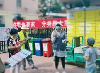  ??  ?? Social Worker Wang Yuan explains trash sorting rules in Zhanlanlu area in Beijing on June 8