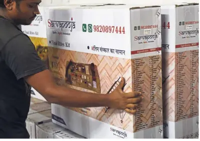  ?? — AFP ?? Flying off the shelves: A worker arranging boxes of the SarvaPooja ‘final rites kit’ at the manufactur­ing unit in Mumbai.