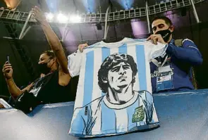  ?? ANDRE COELHO / EFE ?? Un aficionat ensenyant una samarreta amb la imatge de Maradona