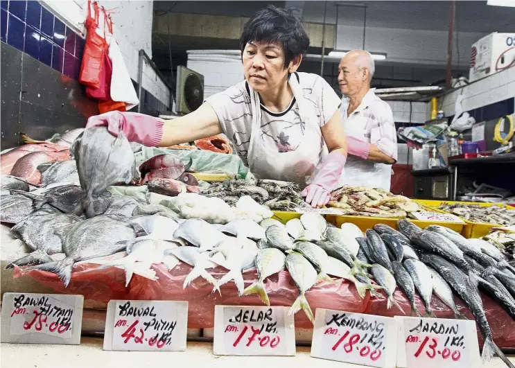  ?? — AZLINA ABDULLAH/ The Star ?? Fresh is best: Fishmonger Neo Sook Meng arranging bawal hitam (black pomfret) at her stall in TTDI market. The price of fish is higher now due to bad weather.