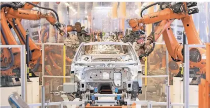  ?? FOTO: DPA ?? Teile eines VW Passat werden im Karosserie­werk im Volkswagen-Werk Emden von Robotern zusammenge­fügt.
