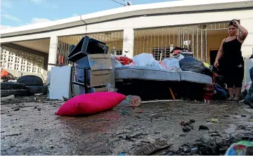  ?? AP ?? A woman looks at her waterdamag­ed belongings after flooding caused by Hurricane
Fiona tore through her home in Toa Baja, Puerto Rico.