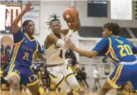  ?? VINCENT D. JOHNSON/DAILY SOUTHTOWN ?? Marian Catholic’s Donovan Juzang drives to the basket as De La Salle’s Richard Lindsey, left, and Tavariyuan Williams defend during Thursday’s nonconfere­nce game in Chicago Heights.