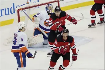  ?? KATHY WILLENS ?? New Jersey Devils center Travis Zajac (19) and Devils left wing Miles Wood (44) react after Devils center Jack Hughes scored a goal against New York Islanders goaltender Ilya Sorokin (30) during the first period of an NHL hockey game against the New York Islanders, Sunday, Jan. 24, 2021, in Newark, N.J. Islanders defenseman Ryan Pulock (6) takes in the reaction.