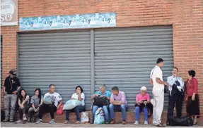  ??  ?? Venezuelan­s wait to board a bus in Caracas, the capital, on their way out of the country to escape a deepening humanitari­an crisis as hyperinfla­tion and acute shortages of food and medicine grip the country. FEDERICO PARRA/AFP/GETTY IMAGES