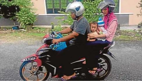  ??  ?? NUR Syafira bersama suami dan dua anaknya menaiki motosikal untuk ke hospital.