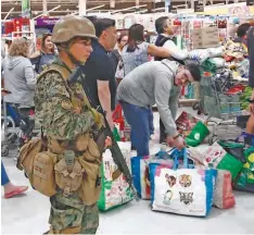  ?? AP ?? La policía militar hace guardia en un supermerca­do mientras los clientes esperan en fila en Santiago, Chile, ayer.
