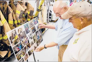  ?? JOHNATHON HENNINGER/SPECIAL TO THE COURANT ?? Michael Furgueson, left, holds a selection of family photos of Joe Heller at a memorial service in Essex on Thursday. His son, also named Michael Furgueson, right, remembers delivering newspapers to the Heller home.