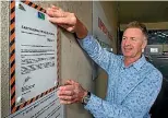  ??  ?? Timaru District Council building control manager Jayson Ellis with an earthquake prone building notice.