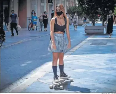  ?? JUAN CARLOS VÁZQUEZ ?? Una joven sobre su monopatín por una céntrica calle de Sevilla, protegida con la mascarilla.