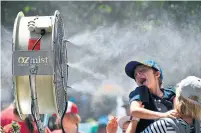  ?? SAEED KHAN AFP/GETTY IMAGES ?? A child cools down in front of a mist fan at the Australian Open on Monday. Temperatur­es reached 30 C early in the day.