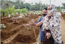  ?? — AFP ?? A mother mourns with her son during her mother’s funeral at the Mulyaharja cemetery for Covid-19 coronaviru­s victims, in Bogor, West Java, on Thursday.