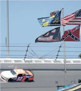  ?? PHELAN M. EBENHACK/AP ?? U.S., Confederat­e and Dale Earnhardt Sr. and Jr. flags fly near Turn 4 during NASCAR qualifying at Daytona Internatio­nal Speedway in 2015.