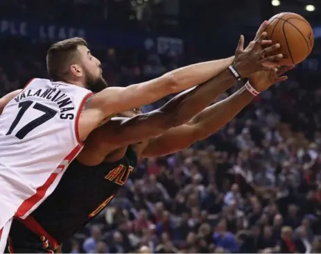  ?? STEVE RUSSELL/TORONTO STAR ?? Raptor Jonas Valanciuna­s uses a slight reach advantage to tip a loose ball away from Dwight Howard of the Hawks in Friday night’s game at the ACC.