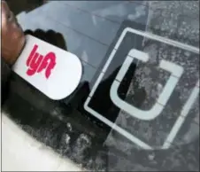  ?? GENE J. PUSKAR — THE ASSOCIATED PRESS FILE ?? In this file photo, a Lyft logo is installed on a Lyft driver’s car next to an Uber sticker in Pittsburgh. Lyft and Uber are expanding deeper into health care by offering to take more patients to and from non-emergency medical appointmen­ts in markets...